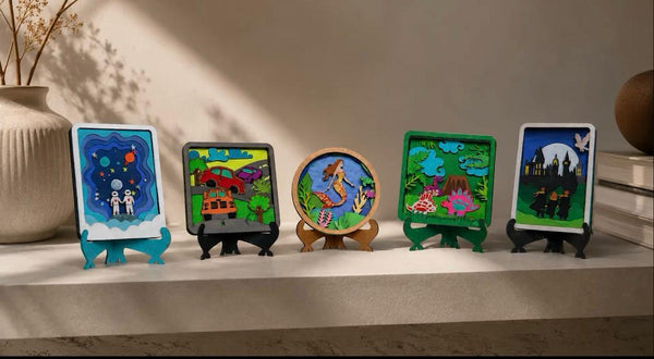Five colorful DIY miniature art frames featuring space, cars, a mermaid, nature, and a magical castle, displayed on decorative stands in a warm, sunlit interior.